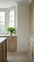 Bright kitchen pantry with natural light from large window, wooden cabinetry, potted green plant on windowsill, neutral walls, and stone flooring for home design inspiration.