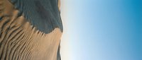 Sand dunes with ripple patterns against clear blue sky, suitable for travel, nature, and desert landscape backgrounds.