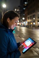 Young woman using tablet computer on city street at night with urban lights and bokeh background for digital lifestyle and mobile technology concepts.