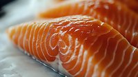 Fresh raw salmon fillet with distinctive orange-pink color and white marbling pattern shown in close-up macro photography, highlighting natural texture and quality.