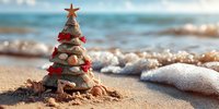 Christmas tree made of seashells and starfish on sandy beach with ocean waves in background, decorated with red ribbons for tropical holiday celebration.