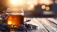 Glowing honey jar with fresh lavender sprigs on rustic wooden table, warm sunset bokeh background creates cozy atmospheric mood for natural wellness concept.