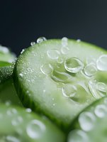 Fresh green cucumber slices with water droplets on dark background for healthy eating and spa concepts.
