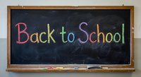 Colorful chalk text Back to School written on dark blackboard with wooden frame for education and learning concepts.