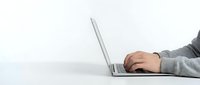 Professional businessman hands typing on modern laptop computer at clean white desk workspace for remote work and digital business productivity.