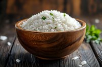 Steamed white rice garnished with fresh herbs in wooden bowl on rustic dark table, close up view of traditional Asian cuisine side dish.