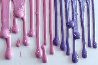 Colorful dripping paint streams in pink and purple creating artistic abstract pattern on white background, perfect for beauty and cosmetic industry designs.