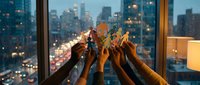 Diverse group of people raising hands together in celebration against illuminated city skyline at dusk, symbolizing teamwork, unity, and shared success in corporate or community settings.
