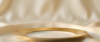 Elegant gold-rimmed plate on soft beige fabric backdrop, suitable for luxury tableware, fine dining, and upscale product photography.