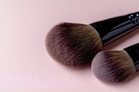 Professional makeup brushes with soft synthetic bristles on pink background, close-up view showing texture and detail for cosmetic application and beauty tutorials.