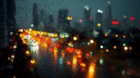 Rainy evening cityscape with colorful bokeh lights through wet glass window creating atmospheric urban mood for backgrounds and design projects.