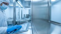 Scientist in protective suit working in sterile pharmaceutical laboratory with modern equipment and clean room environment for drug development.