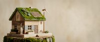 Sustainable eco house model with solar panels, wind turbine and green roof on natural wooden base representing renewable energy and environmental living.