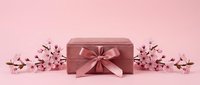 Pink velvet gift box with satin bow surrounded by cherry blossom branches on pastel pink background, perfect for holiday and celebration concepts.