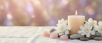 Spa wellness scene with burning candle, white flowers, smooth stones and soft bokeh background for relaxation and meditation concepts.