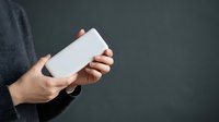 Person of South Asian descent holding blank white rectangular card or device mockup against gray background for branding and marketing purposes.