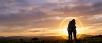 Romantic couple silhouette embracing at sunset with golden sky and mountain landscape creating intimate moment for love and relationship concepts.