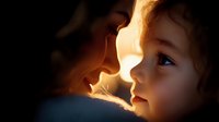 Tender moment between mother and daughter in dramatic lighting, faces close together with warm backlight creating silhouette effect and highlighting facial features.