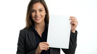 Young woman with long brown hair and fair complexion wearing a black blazer holds a blank white card or document against a white background, smiling at camera for business, marketing, or corporate messaging use.