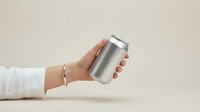 Female hand holding blank aluminum beverage can mockup on neutral background for branding design and product presentation purposes.