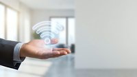 Businessman holding hand with wifi symbol glowing above palm in modern office space, representing wireless connectivity and digital technology solutions.