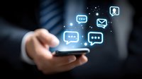 Hand holding smartphone with glowing blue chat bubbles and messaging icons floating above screen, illustrating digital communication and mobile messaging technology.