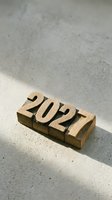 Wooden blocks spelling 2021 on concrete surface with natural lighting and shadows for year concept design.