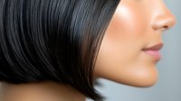 Side profile close up of Asian woman with straight black bob haircut showing glossy lips and smooth skin against gray background, beauty concept.