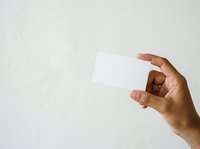 Hand holding blank white business card against neutral background, isolated on light backdrop for branding, marketing, and corporate identity design use.