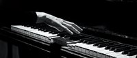 Hand playing piano keys in dramatic black and white, capturing the elegance of classical music performance and artistic expression.