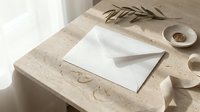 Elegant white envelope on marble surface with dried olive branch and wax seal creating sophisticated stationery mockup for wedding invitations.