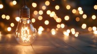 Glowing light bulb on wooden surface against blurred warm bokeh background creates cozy atmospheric mood. Concept of creativity and inspiration.