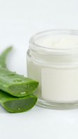 Natural aloe vera moisturizing cream in glass jar with fresh green aloe leaves on white background for skincare and beauty products.
