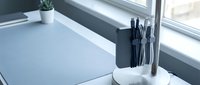 Minimalist desk setup with black pens and pencils in white ceramic holder near window with natural light for modern office workspace design.