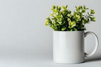 Fresh green artificial plant in white ceramic mug against light gray background, minimalist home decor composition with copy space for text.