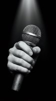 Hand holding microphone in dramatic spotlight on black background for music performance and entertainment industry.