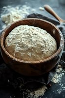 Fresh wheat flour in rustic wooden bowl with wooden spoon on dark surface for baking and cooking preparation.