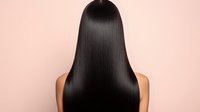 Smooth, glossy black hair from behind on beige background, showcasing healthy, straight hairstyle for beauty salon advertising or hair care product promotion.