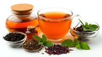 Cup of aromatic tea with fresh mint leaves, dry black and herbal tea varieties in glass bowls and wooden spoons on white background.