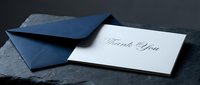 Elegant thank you card with navy blue envelope on dark stone surface, classic calligraphy script, formal stationery for weddings, events, and corporate gifting.