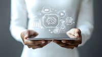 Young Asian businesswoman hands holding tablet with glowing brain and business icons floating above, representing digital transformation and artificial intelligence.