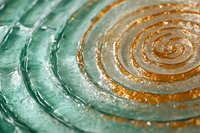 Textured glass surface with concentric circular patterns in green and amber tones creating ripple effects for modern interior design and decorative applications.