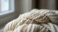 Coiled natural rope with thick twisted fibers in soft beige color, close-up macro shot showing detailed texture for nautical and craft projects.