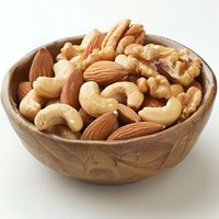 Mixed raw nuts including cashews, almonds and walnuts in wooden carved bowl on white background, healthy protein snack for nutrition and diet.