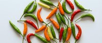Fresh colorful chili peppers scattered on white background. Hot spicy vegetables for cooking, seasoning and culinary ingredients isolated for design use.