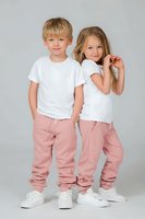 Young boy and girl wearing white t-shirts and pink sweatpants standing together on gray background. Casual children's fashion and lifestyle concept.