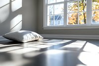 Sunlight streaming through window casting geometric shadows on bed with white pillow, autumn trees visible outside, minimalist bedroom interior design.