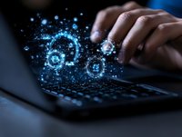 Hands typing on laptop keyboard with glowing blue digital transformation icons and network connections floating above in dark environment.