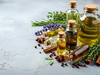 Natural aromatherapy essential oils in glass bottles with fresh herbs, spices and lavender flowers on textured background for wellness and spa treatments.