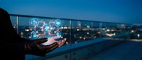 Businessman holding smartphone with glowing network icons against city skyline at dusk. Digital connectivity and modern technology concept for business.